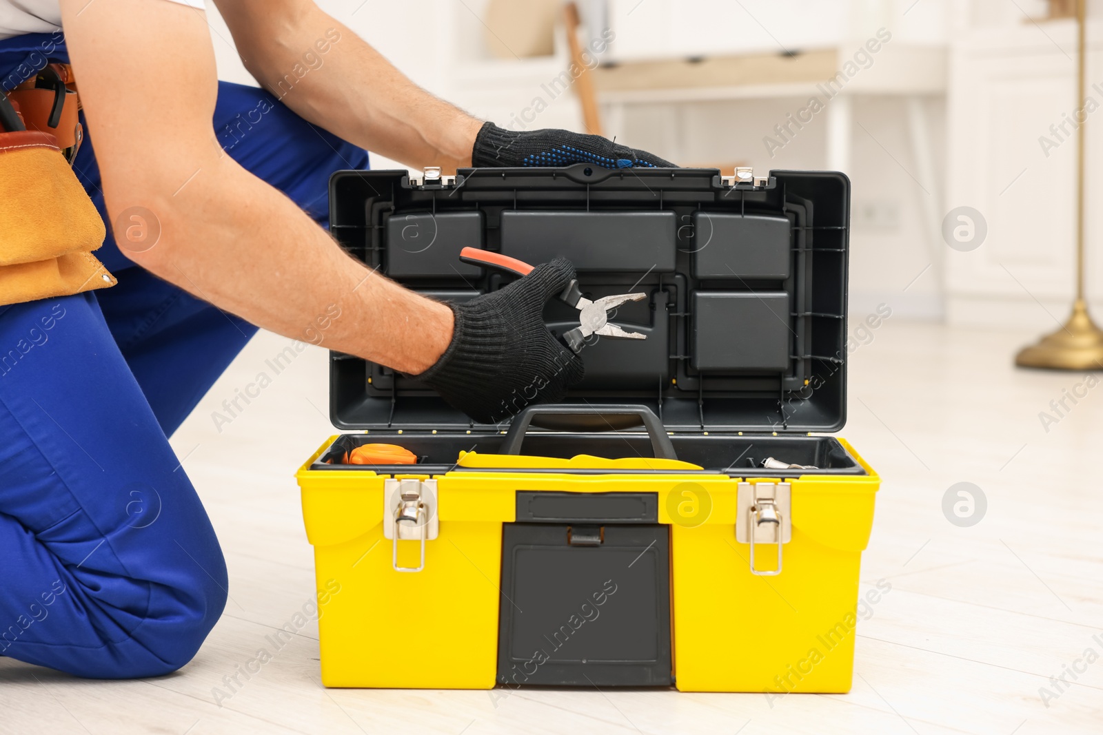 Professional repairman with tool box and pliers indoors, closeup Photo of Professional repairman with tool box and pliers indoors, closeup
