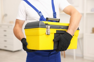 Photo of Professional repairman with tool box indoors, closeup