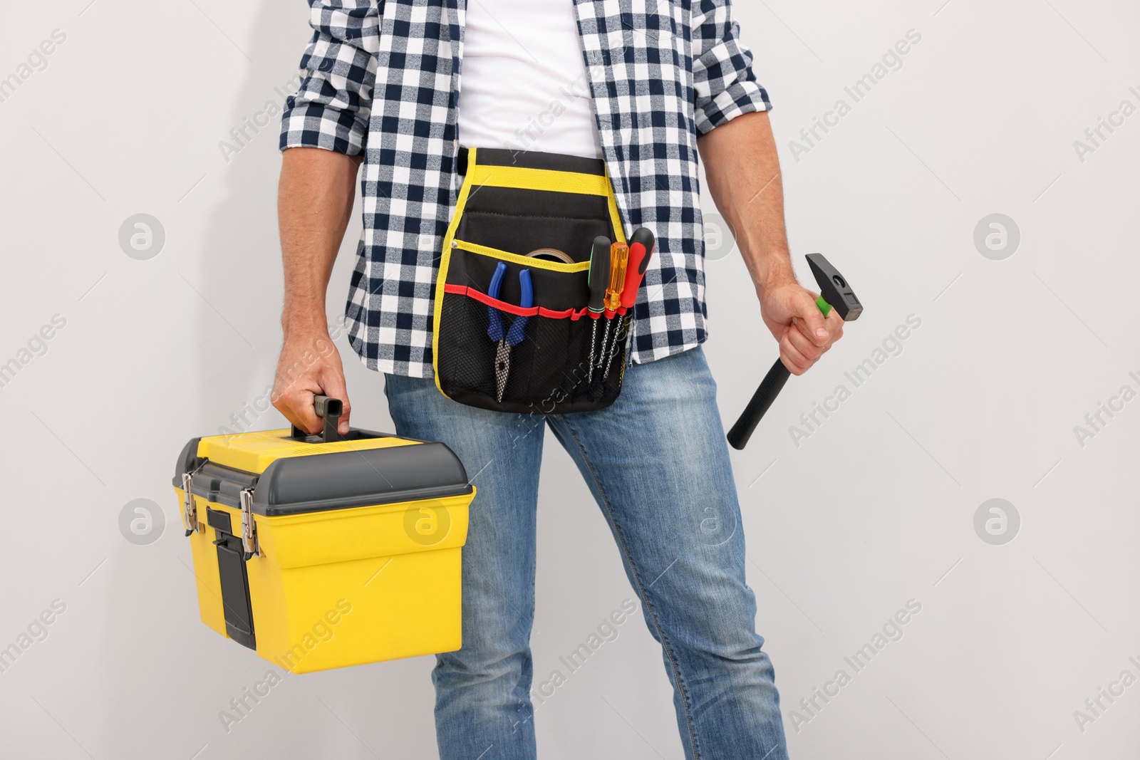 Professional repairman with tool box and hammer on light grey background, closeup Photo of Professional repairman with tool box and hammer on light grey background, closeup
