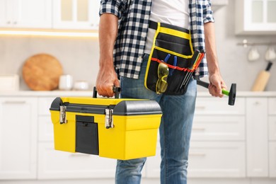 Photo of Professional repairman with tool box and hammer indoors, closeup
