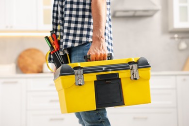Photo of Professional repairman with tool box indoors, closeup