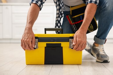 Photo of Professional repairman with tool box indoors, closeup
