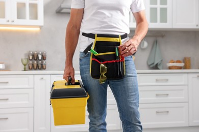 Photo of Professional repairman with tool box indoors, closeup