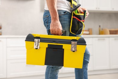 Photo of Professional repairman with tool box indoors, closeup