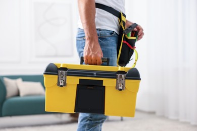 Photo of Professional repairman with tool box indoors, closeup