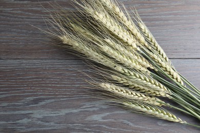 Photo of Green wheat spikes on wooden table, flat lay. Space for text