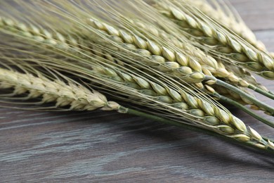 Photo of Green wheat spikes on wooden table, closeup