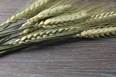 Photo of Green wheat spikes on wooden table, closeup