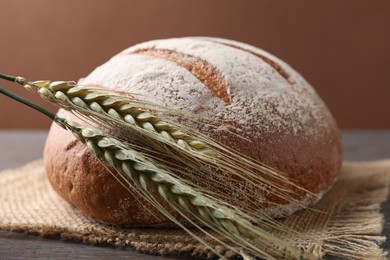 Photo of Fresh bread and green wheat spikes on table, closeup