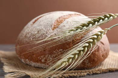 Photo of Fresh bread and green wheat spikes on table, closeup