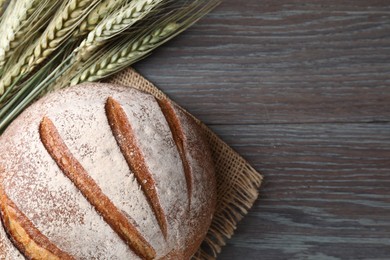 Photo of Fresh bread and green wheat spikes on wooden table, flat lay. Space for text