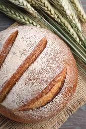 Photo of Fresh bread and green wheat spikes on table, flat lay