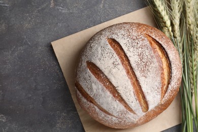 Photo of Fresh bread and green wheat spikes on grey table, flat lay. Space for text