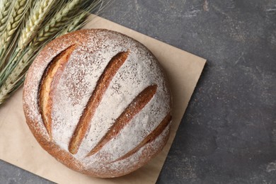 Photo of Fresh bread and green wheat spikes on grey table, flat lay. Space for text