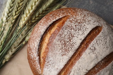 Photo of Fresh bread and green wheat spikes on grey table, flat lay