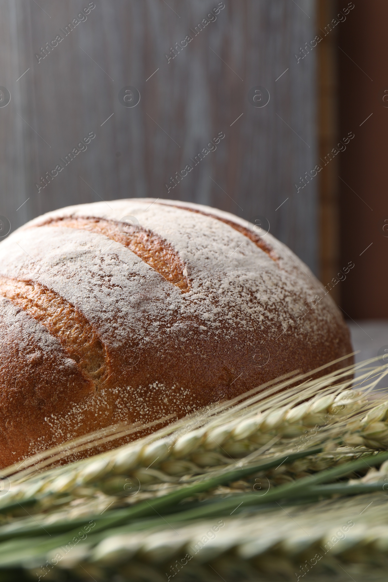Photo of Fresh bread and green wheat spikes on table, closeup