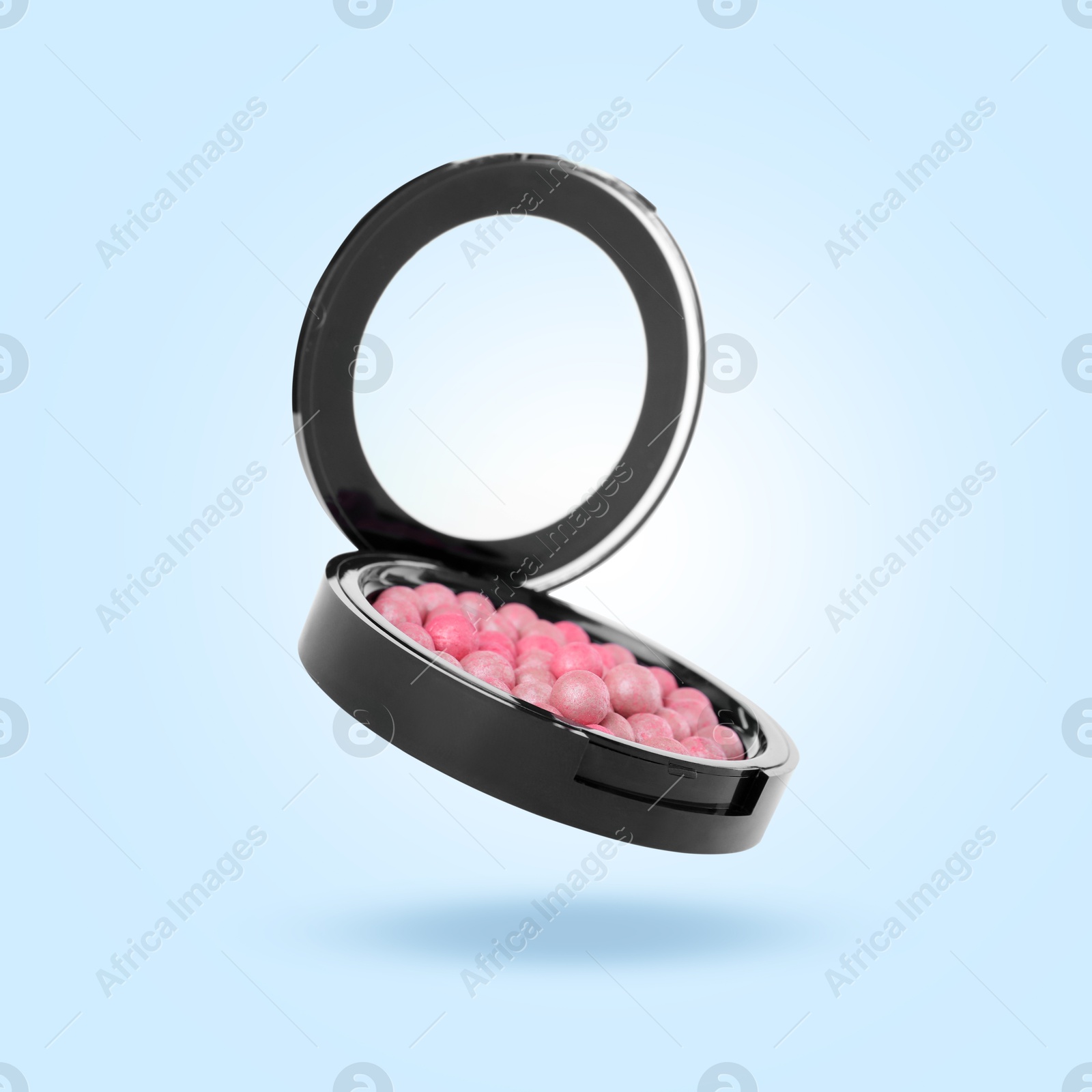 Image of Blush pearls in air against light blue background. Makeup cosmetics