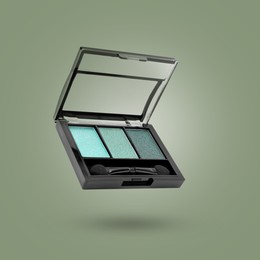 Image of Eyeshadow palette in air against sage color background. Makeup cosmetics
