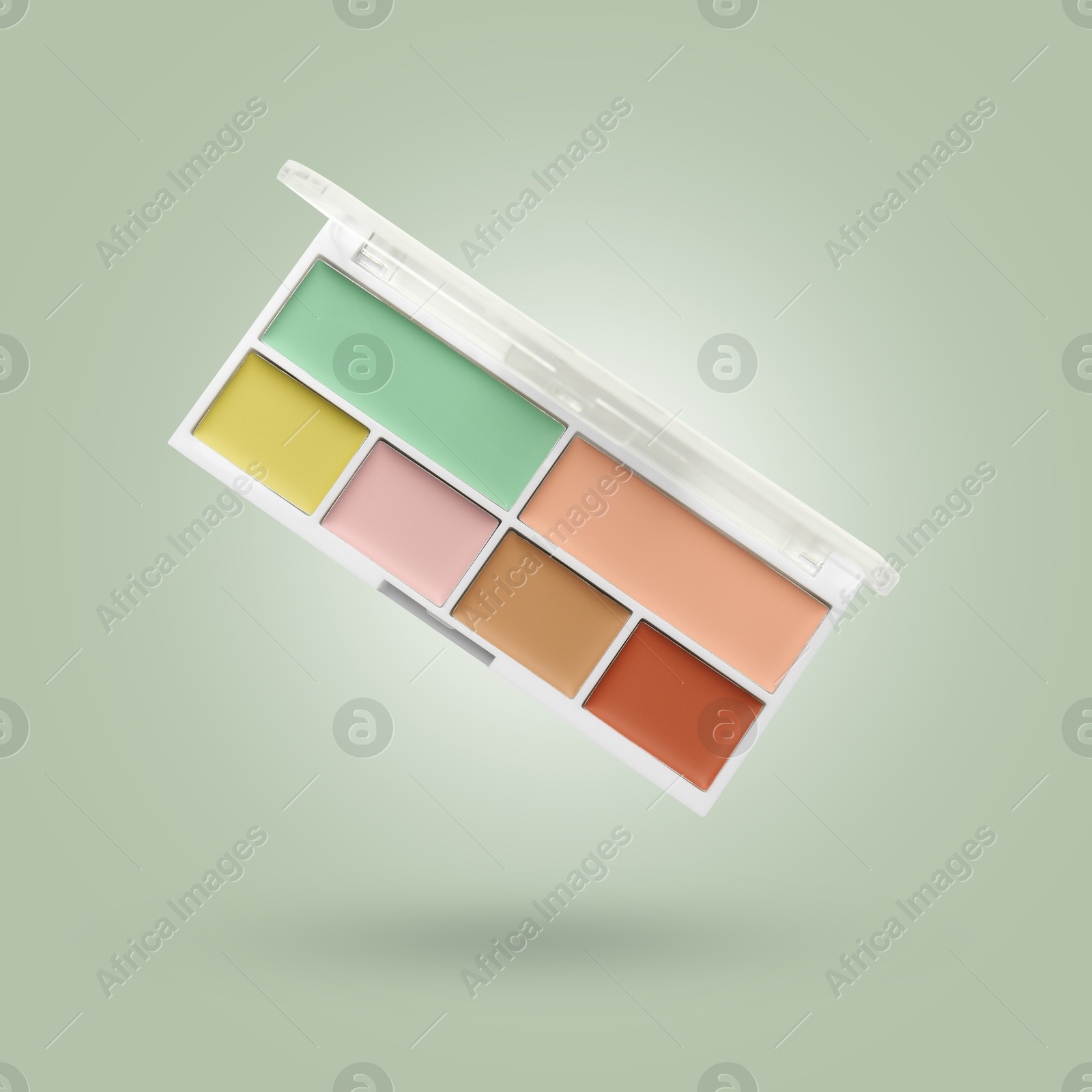 Image of Concealer palette in air against sage color background. Makeup cosmetics