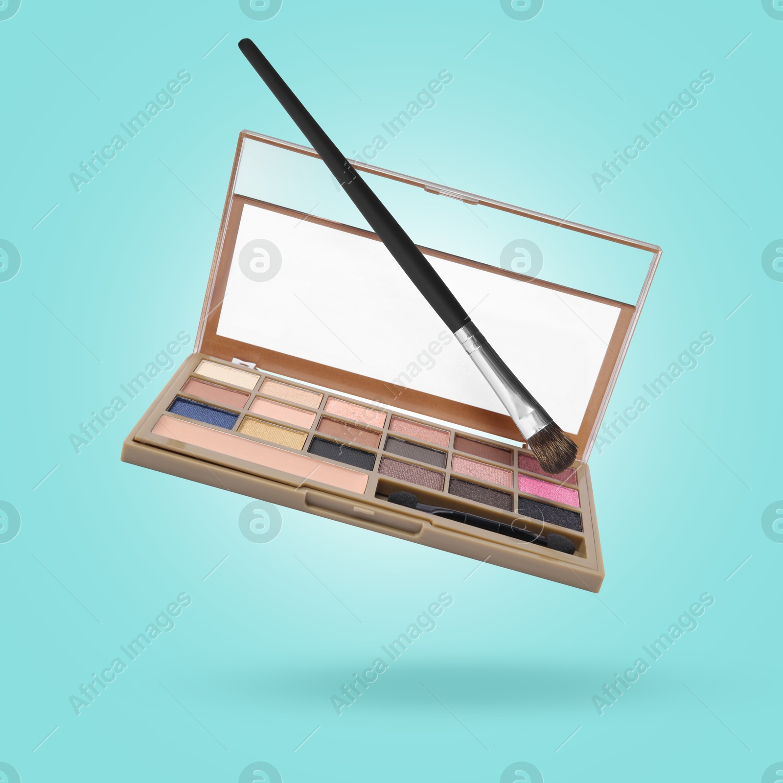 Image of Eyeshadow palette and brush in air against light blue background. Makeup cosmetics
