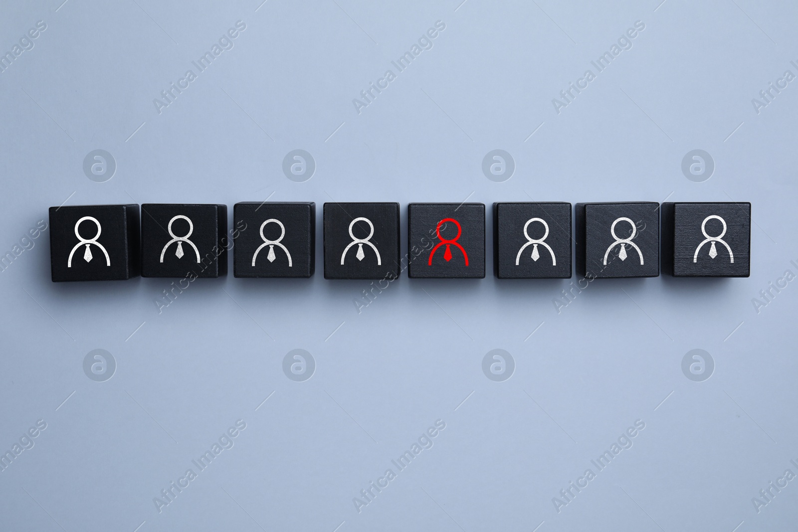 Image of Dismissal. Black cube with red human icon among others with white ones on grey background, top view