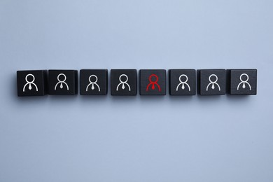 Image of Dismissal. Black cube with red human icon among others with white ones on grey background, top view