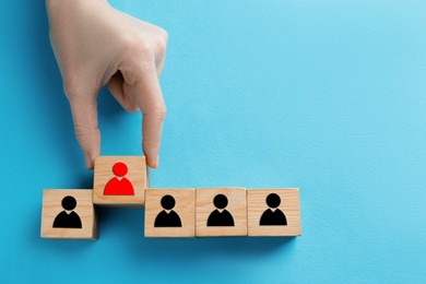 Image of Dismissal. Woman taking cube with red human icon among others with black ones on light blue background, top view