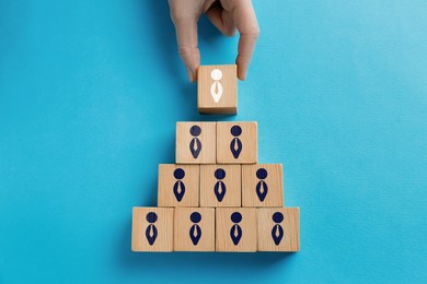 Image of Dismissal. Woman taking cube with white human icon among others on light blue background, top view