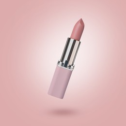 Image of Lipstick in air against pink background. Makeup cosmetics