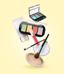 Image of Different makeup products in air against pale yellow background