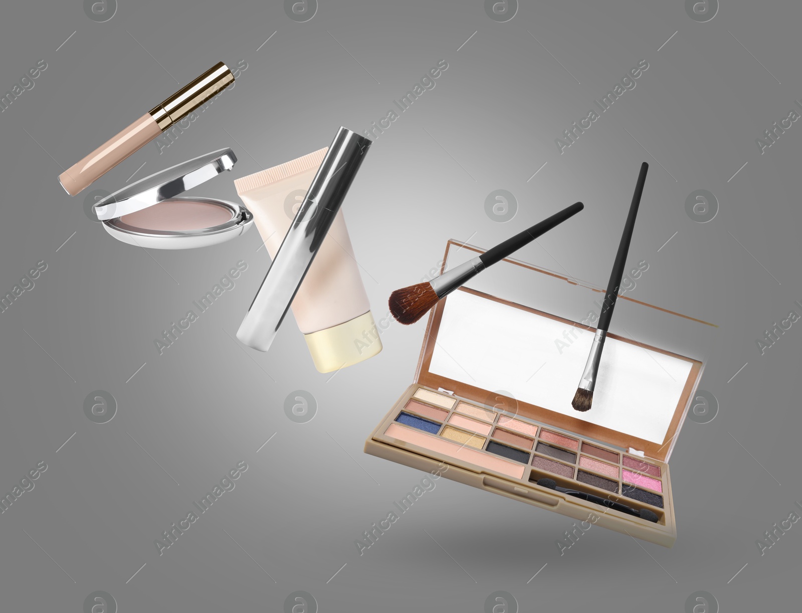 Image of Eyeshadow palette and other makeup products in air against grey background