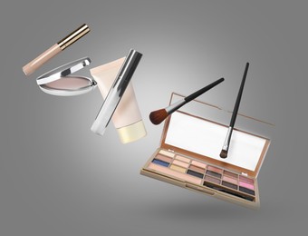 Image of Eyeshadow palette and other makeup products in air against grey background
