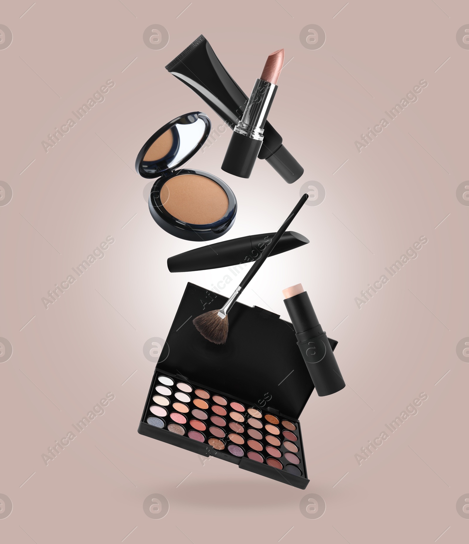 Image of Eyeshadow palette and other makeup products in air against beige grey background