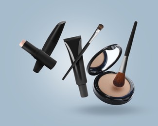 Image of Different makeup cosmetics in air against light blue background
