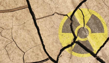 Image of Yellow radioactive sign on cracked dry earth, top view. Radiological pollution