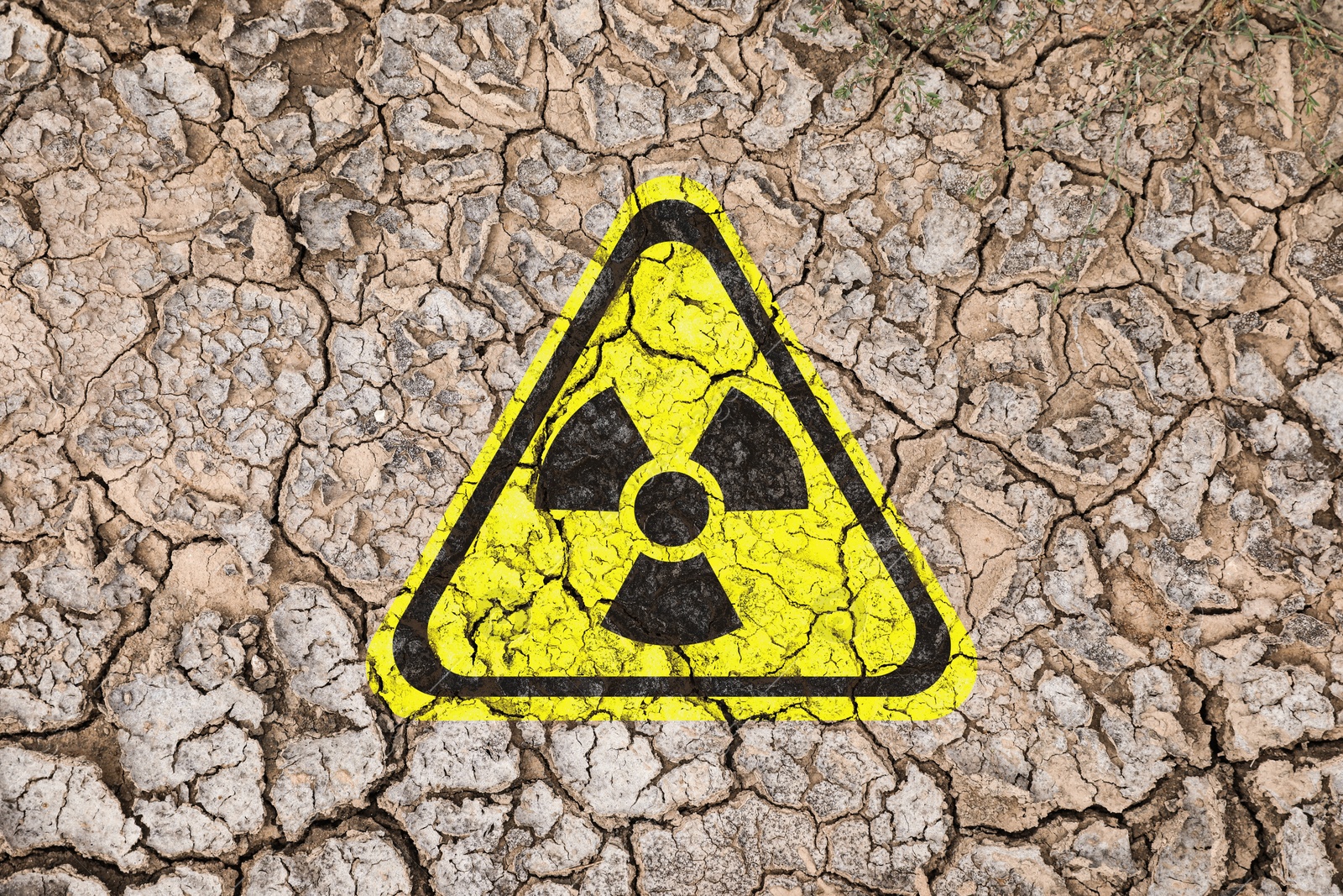 Image of Yellow radioactive sign on cracked dry earth, top view. Radiological pollution