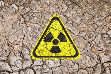 Image of Yellow radioactive sign on cracked dry earth, top view. Radiological pollution