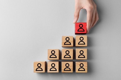 Image of Dismissal. Woman taking red cube with human icon among others on white background, top view