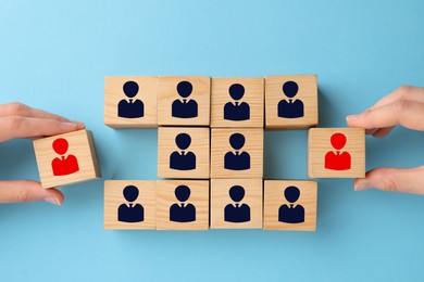 Image of Dismissal. Women taking cubes with red human icons among others on light blue background, top view