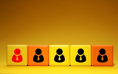 Image of Dismissal. Cube with red human icon among others with black ones on orange background