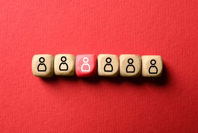 Image of Dismissal. Red cube with white human icon among others with black ones on red background, top view