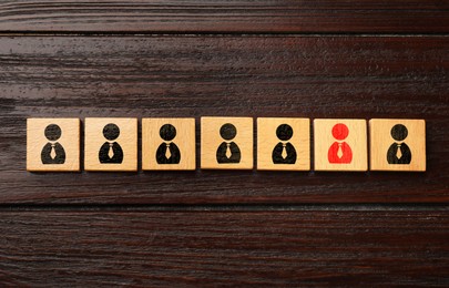 Image of Dismissal. Cube with red human icon among others with black ones on wooden background, top view