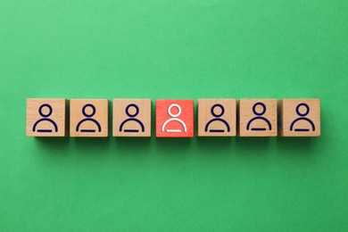 Image of Dismissal. Red cube with white human icon among others with blue ones on green background, top view