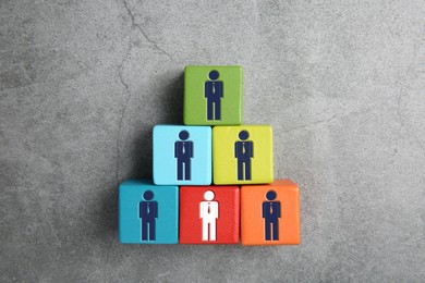 Image of Dismissal. Red cube with white human icon among others with blue ones on grey background, top view