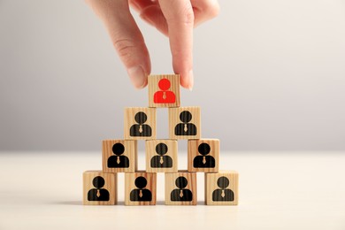 Image of Dismissal. Woman taking cube with red human icon among others with black ones on table, closeup
