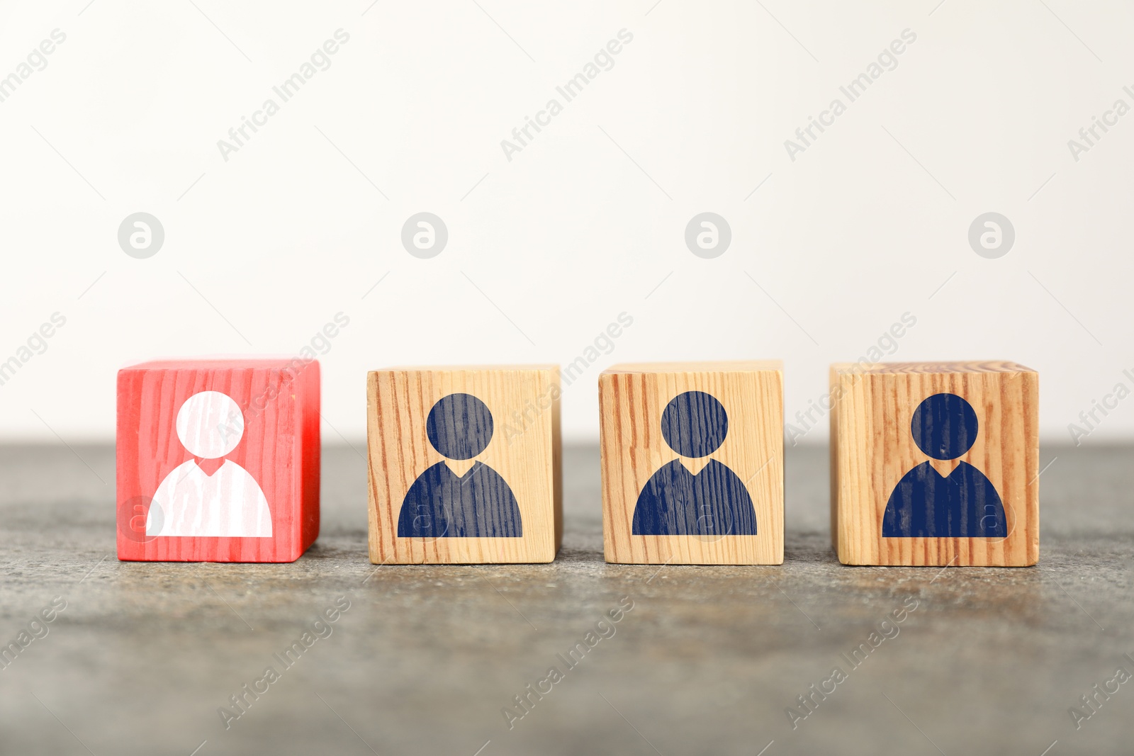 Image of Dismissal. Red cube with white human icon among others with blue ones on table