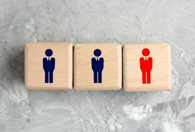 Image of Dismissal. Cube with red human icon among others with blue ones on grey background, top view