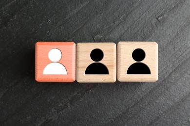 Image of Dismissal. Red cube with white human icon among others with black ones on grey textured background, top view
