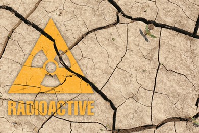 Image of Orange radioactive sign on cracked dry earth, top view. Radiological pollution