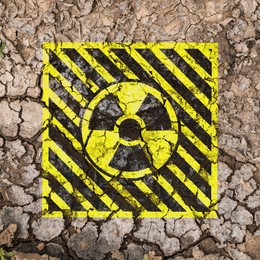 Image of Yellow radioactive sign on cracked dry earth, top view. Radiological pollution